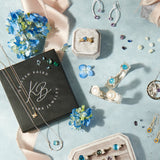 Jewelry set with earrings, necklaces, and a book on a light blue background